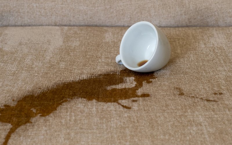 Coffee spill on a fabric sofa requiring careful cleaning.
