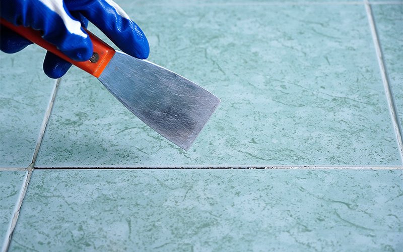 Doctor Clean scraping debris to deep clean ceramic tiles.