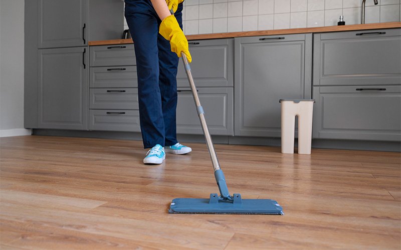 Professional safely deep cleaning kitchen laminate floors with mop.