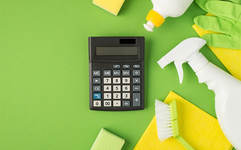 Calculator and cleaning supplies on a green background.