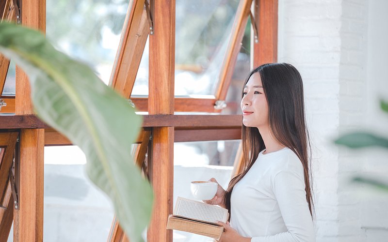 Woman relaxing near wooden window frames with good ventilation.