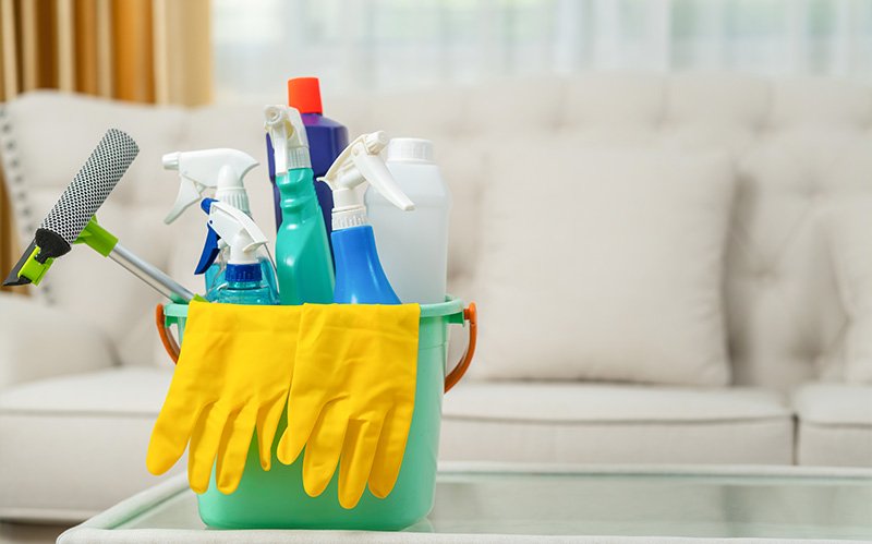 Bucket of cleaning tools in a living room.