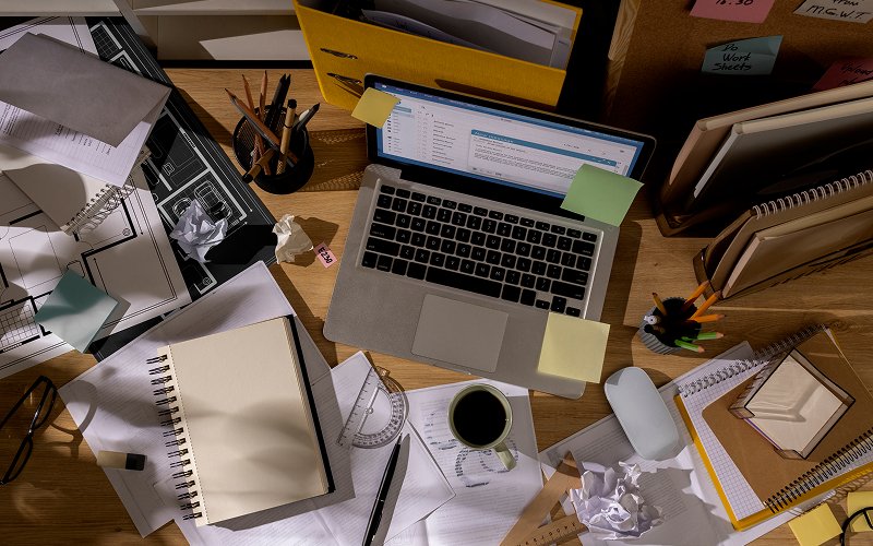 Cluttered and messy workplace desk requiring office cleaning services.