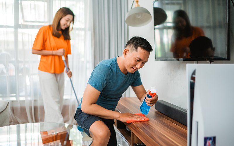 Couple removing dust from furniture in a Singapore home.