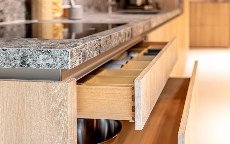 Modern custom wooden cabinetry with open drawers showing raw composite wood layers.