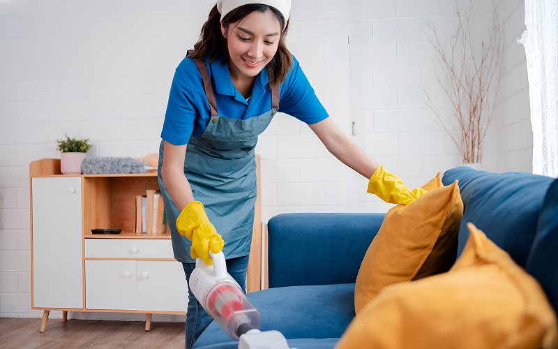 Professional vacuuming sofa to improve house cleanliness.