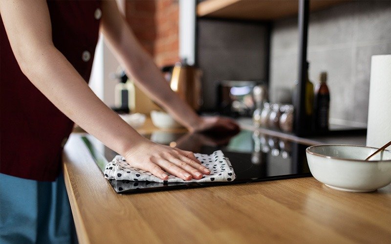 Person wiping down a clean kitchen glass stove