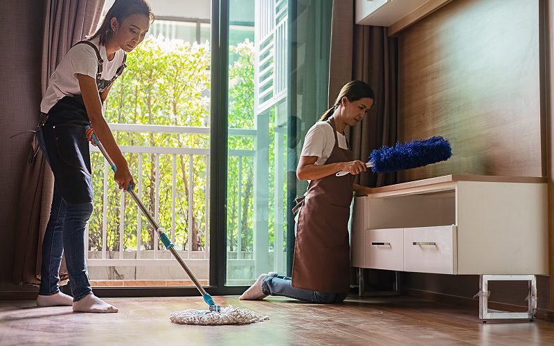 Cleaners mopping floor and dusting furniture.